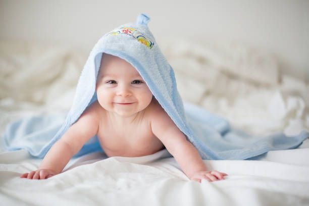 cute-little-baby-boy-relaxing-in-bed-after-bath-smiling-happily8520094501858472381.jpg